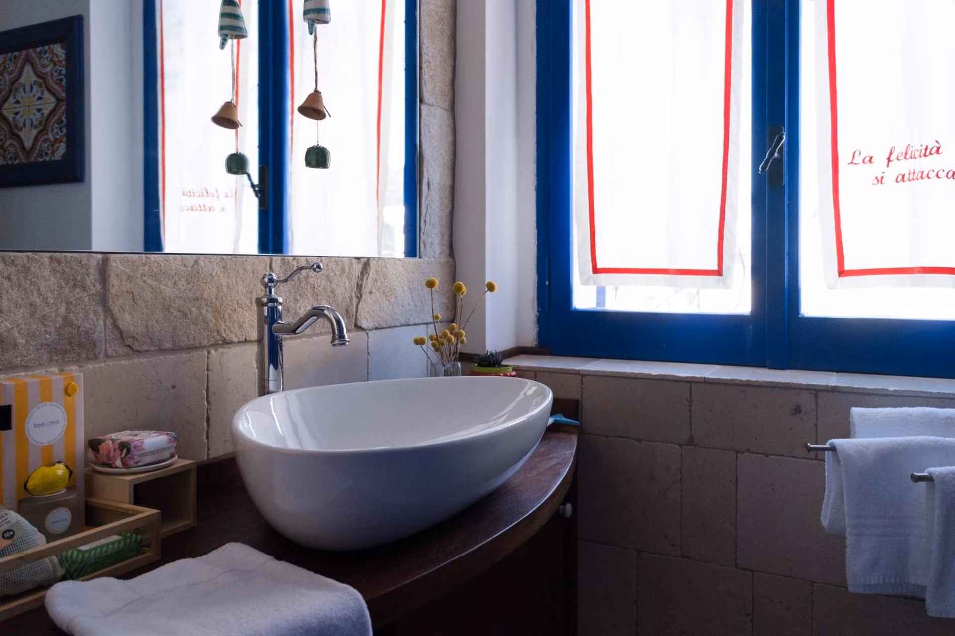 Bagno privato con lavabo a ciotola bianca e finestra blu